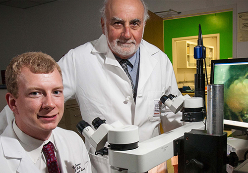 Dr. Byrne with grad student pose behind a microscope.