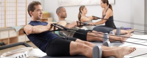 3 adults doing rowing exercises on the floor with an instructor