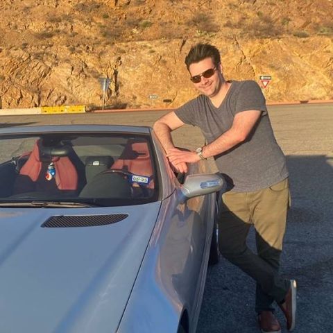 Jose Perez, UT System's Senior Development Specialist, poses next to his car.